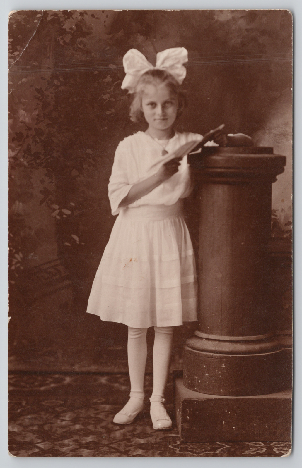 Real Photo Postcard Girl with Big Bow in Studio Holding Book c1910 RPPC